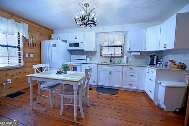 kitchen featuring hardwood / wood-style floors, white appliances, sink, hanging light fixtures, and white cabinetry