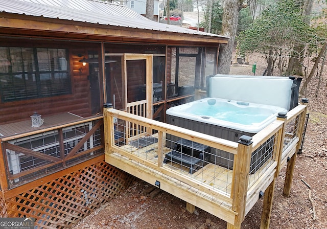 wooden deck with a sunroom and a hot tub