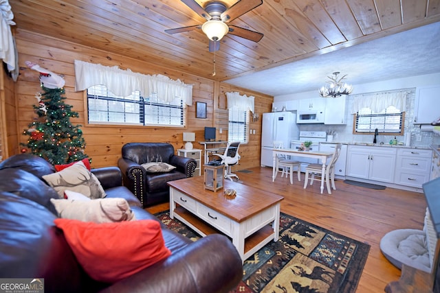 living room with plenty of natural light, sink, ceiling fan with notable chandelier, and light hardwood / wood-style flooring