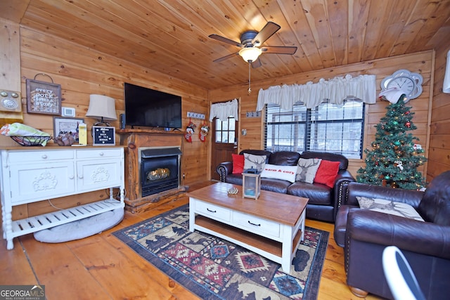 living room featuring light hardwood / wood-style floors, ceiling fan, wood walls, and wood ceiling