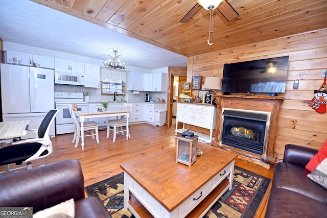 living room with sink, light hardwood / wood-style floors, wooden walls, and wood ceiling