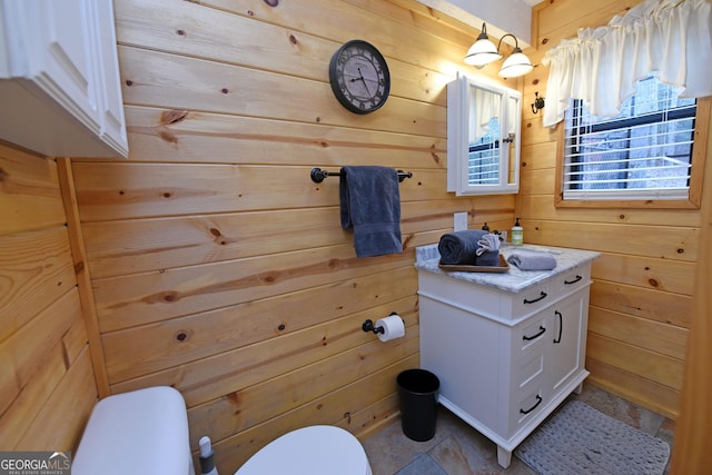 bathroom with vanity, toilet, and wooden walls