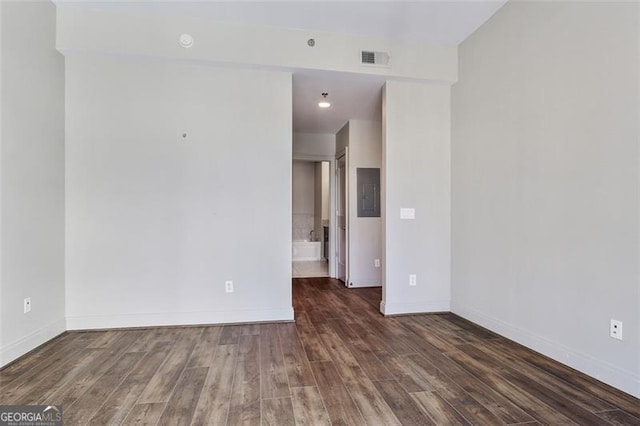 spare room featuring electric panel and dark hardwood / wood-style flooring