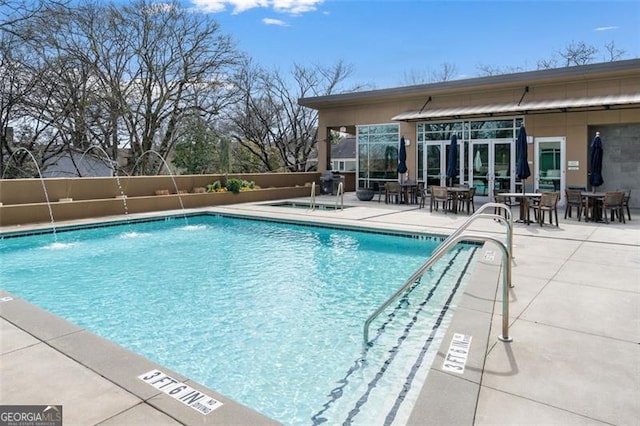 view of swimming pool with pool water feature, a patio, and french doors