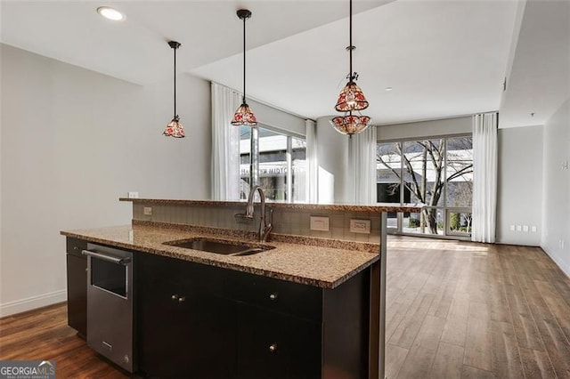 kitchen featuring decorative light fixtures, sink, plenty of natural light, and an island with sink