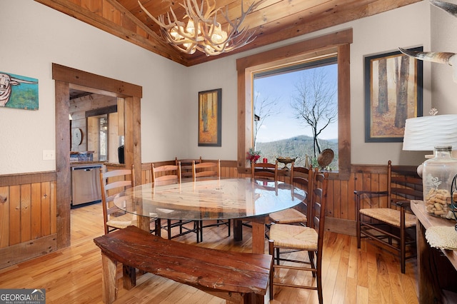 dining room featuring wood ceiling, wooden walls, an inviting chandelier, light hardwood / wood-style flooring, and a mountain view