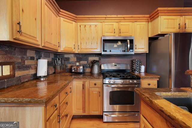 kitchen featuring tasteful backsplash, stainless steel appliances, light brown cabinetry, and wooden counters