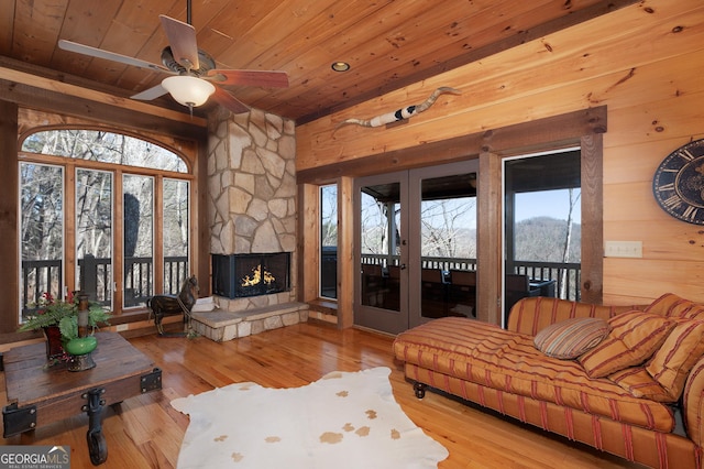 living room with ceiling fan, a fireplace, wood ceiling, and light wood-type flooring