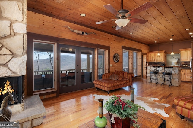 living room featuring wood walls, french doors, light hardwood / wood-style flooring, ceiling fan, and wood ceiling