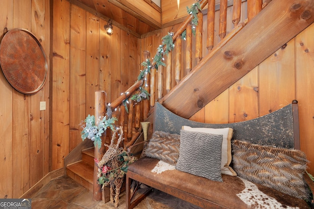 stairway featuring wooden walls