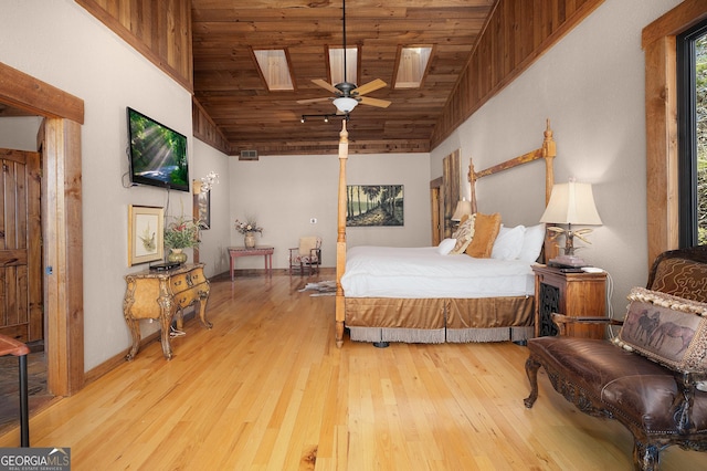 bedroom featuring lofted ceiling with skylight, ceiling fan, wooden ceiling, and light hardwood / wood-style flooring