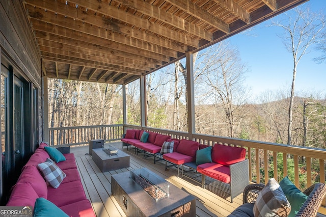 wooden terrace with an outdoor living space with a fire pit