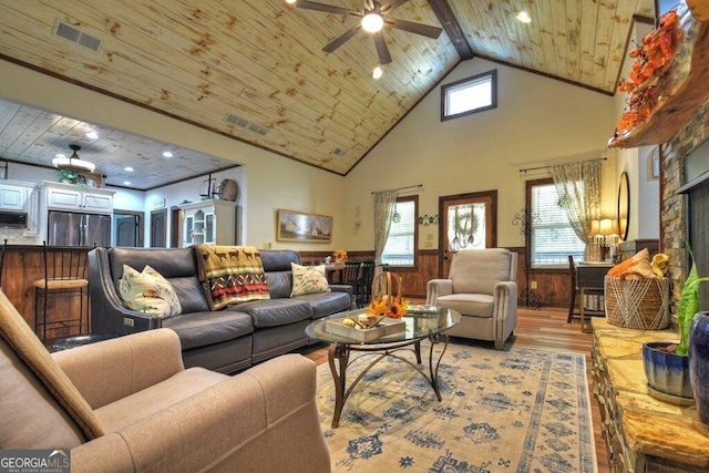 living room featuring wooden ceiling, a high ceiling, wooden walls, light hardwood / wood-style flooring, and ceiling fan