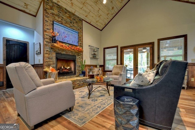 living room with a stone fireplace, wood ceiling, high vaulted ceiling, and french doors