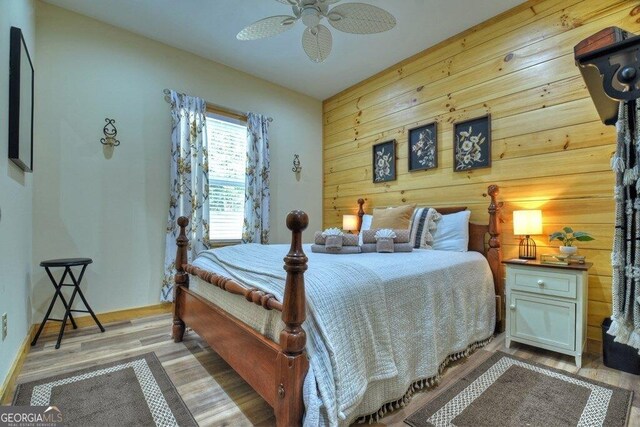 bedroom featuring wood walls, light hardwood / wood-style flooring, and ceiling fan