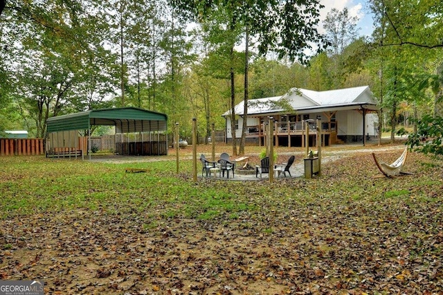 view of yard featuring a fire pit, a carport, and a wooden deck