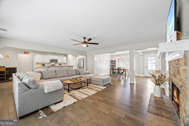 living room with ceiling fan, a fireplace, and dark hardwood / wood-style floors