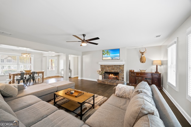 living room with ceiling fan, a fireplace, and dark wood-type flooring