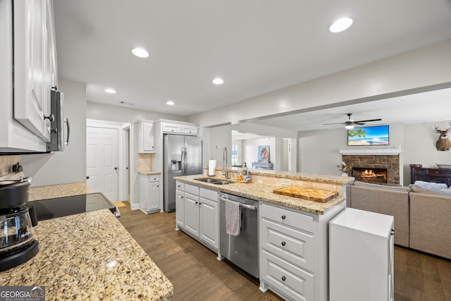 kitchen featuring a center island with sink, white cabinets, sink, ceiling fan, and appliances with stainless steel finishes