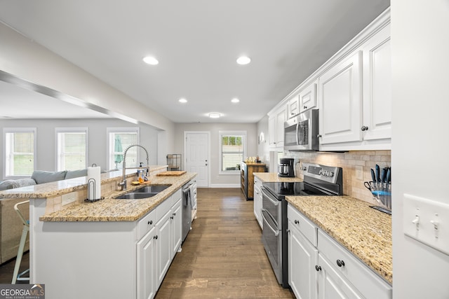 kitchen featuring white cabinetry, sink, dark wood-type flooring, a breakfast bar, and appliances with stainless steel finishes