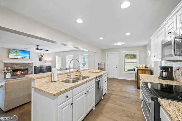 kitchen with ceiling fan, sink, appliances with stainless steel finishes, white cabinets, and hardwood / wood-style flooring