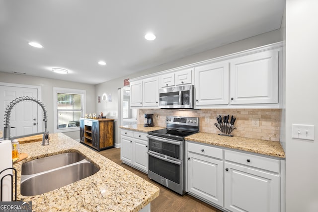 kitchen with appliances with stainless steel finishes, dark hardwood / wood-style flooring, tasteful backsplash, sink, and white cabinetry