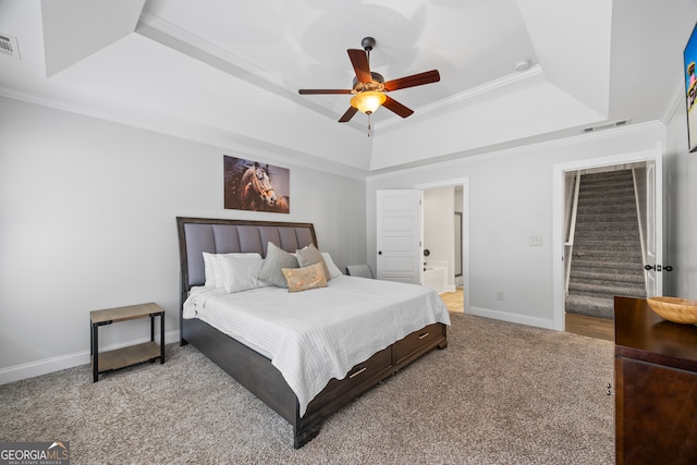 carpeted bedroom with connected bathroom, a tray ceiling, ceiling fan, and crown molding