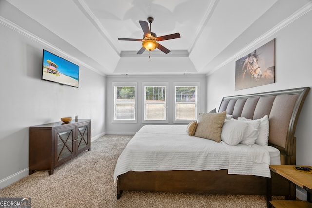 carpeted bedroom with a tray ceiling, ceiling fan, and ornamental molding