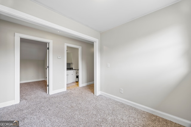 unfurnished bedroom featuring light carpet and ensuite bathroom