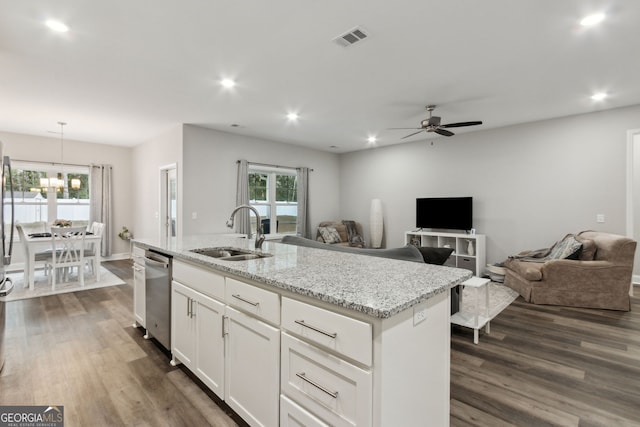 kitchen with white cabinetry, sink, light stone counters, an island with sink, and decorative light fixtures