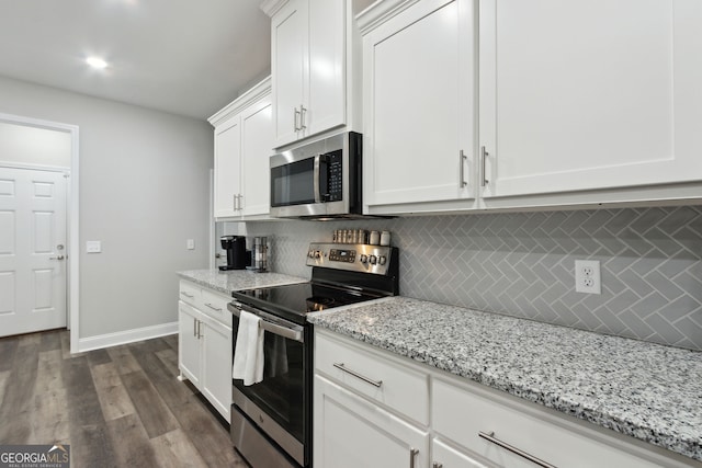 kitchen with light stone countertops, appliances with stainless steel finishes, backsplash, dark hardwood / wood-style flooring, and white cabinetry