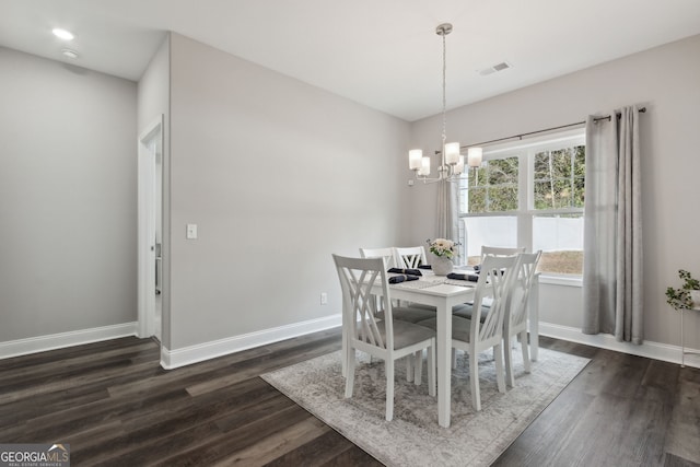 dining room with dark wood-type flooring and a notable chandelier