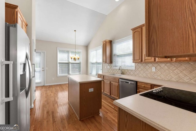 kitchen featuring a kitchen island, tasteful backsplash, appliances with stainless steel finishes, lofted ceiling, and a sink