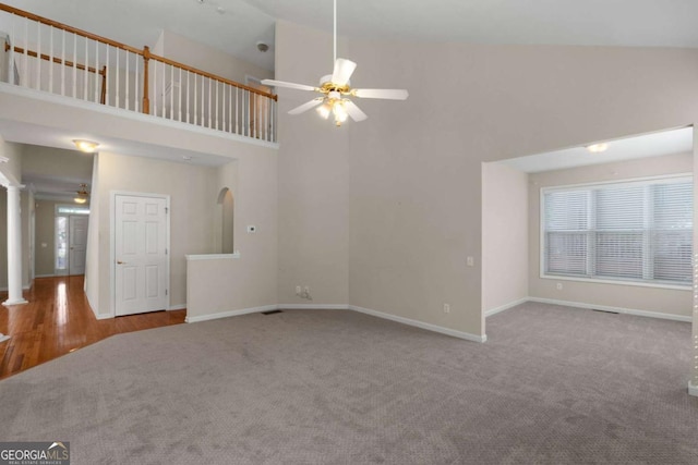unfurnished living room featuring baseboards, high vaulted ceiling, carpet flooring, and a ceiling fan
