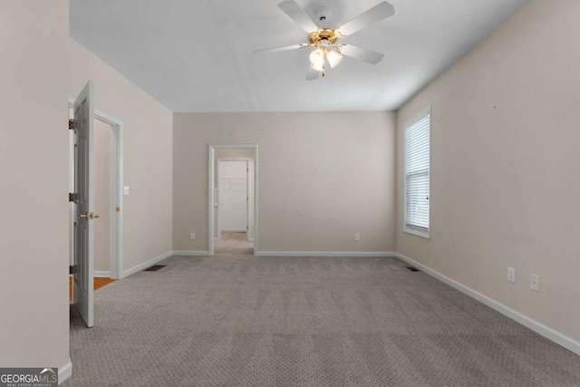 carpeted empty room with baseboards, visible vents, and ceiling fan