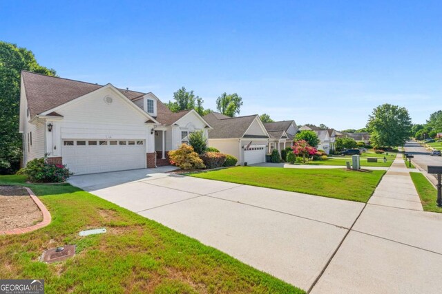 view of front of home with an attached garage, a front yard, brick siding, a residential view, and driveway