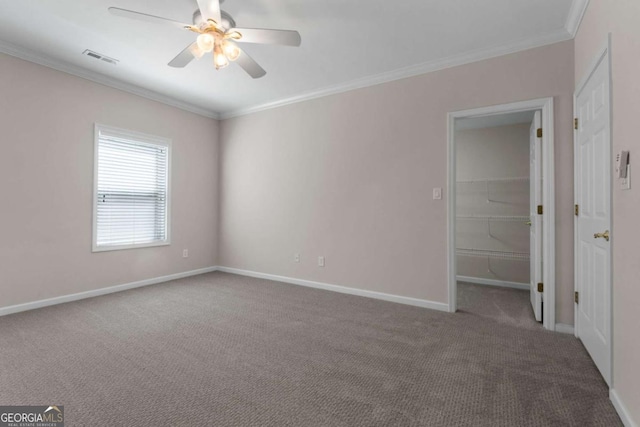 carpeted empty room featuring baseboards, visible vents, crown molding, and ceiling fan