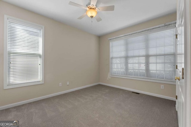 spare room with baseboards, visible vents, ceiling fan, and carpet