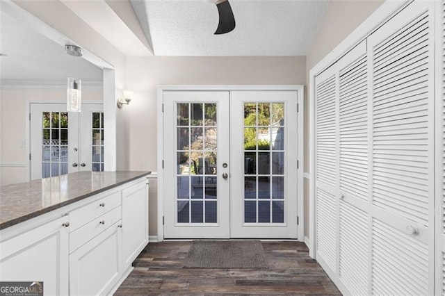 doorway featuring ceiling fan, french doors, dark wood-type flooring, and a textured ceiling