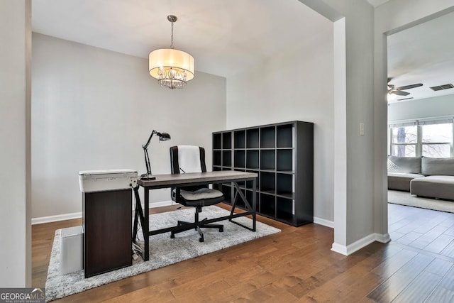 office area with ceiling fan with notable chandelier and dark hardwood / wood-style floors