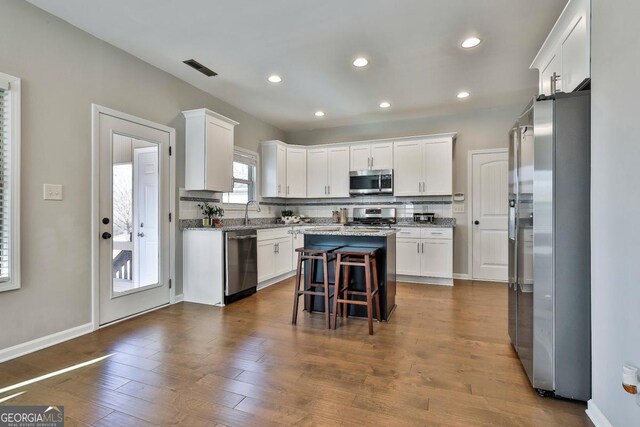 kitchen with white cabinetry, stainless steel appliances, tasteful backsplash, a breakfast bar, and a kitchen island