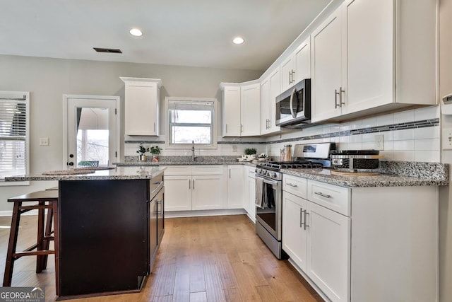 kitchen with light stone countertops, white cabinetry, a center island, and stainless steel appliances