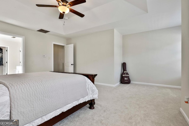 carpeted bedroom featuring a tray ceiling and ceiling fan