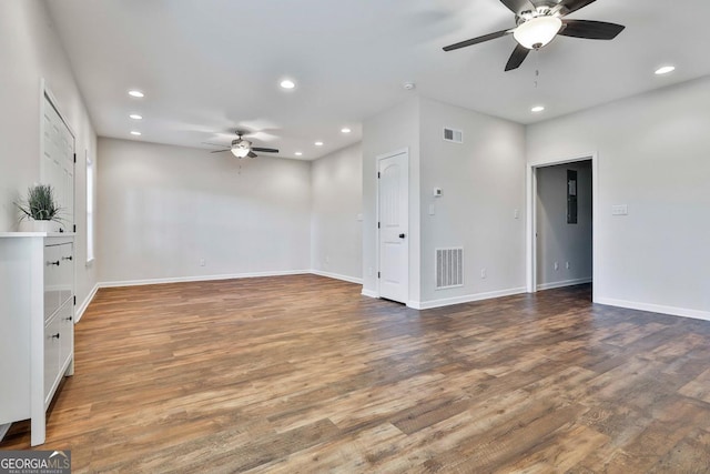 unfurnished living room featuring ceiling fan and dark wood-type flooring