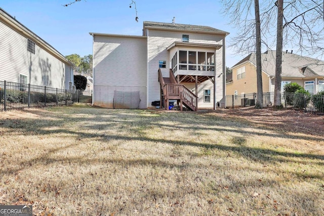 rear view of house featuring a lawn and a sunroom