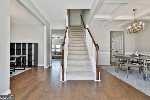 staircase featuring beam ceiling, an inviting chandelier, coffered ceiling, and hardwood / wood-style floors