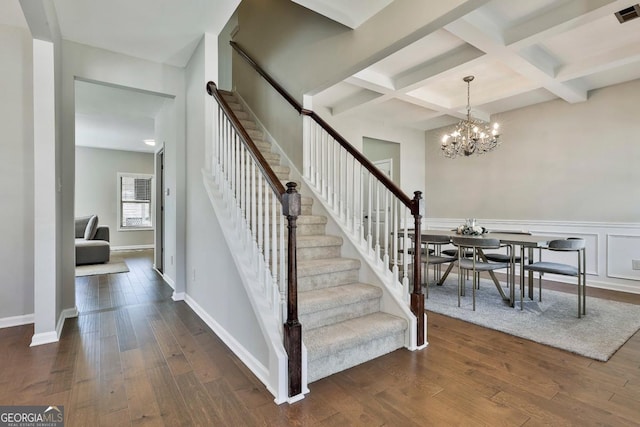 stairs featuring beam ceiling, a chandelier, coffered ceiling, and hardwood / wood-style flooring