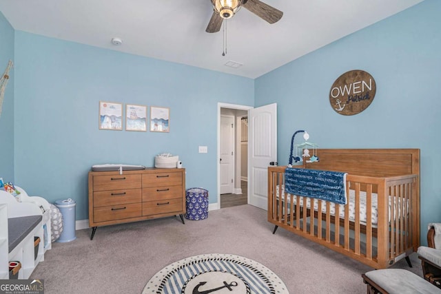 bedroom featuring ceiling fan, light colored carpet, and a crib