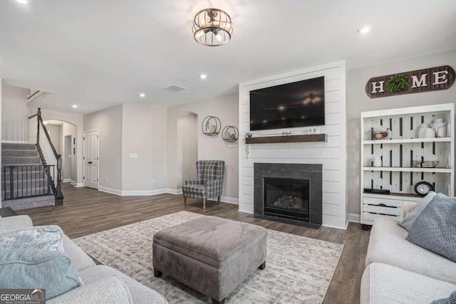 living room with a fireplace and dark wood-type flooring