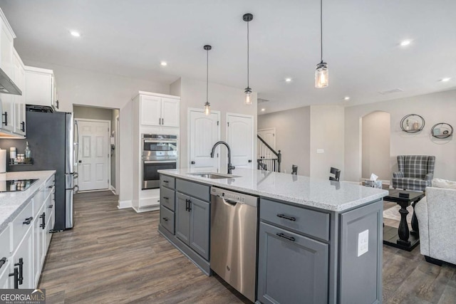 kitchen featuring a kitchen island with sink, white cabinets, sink, appliances with stainless steel finishes, and dark hardwood / wood-style flooring